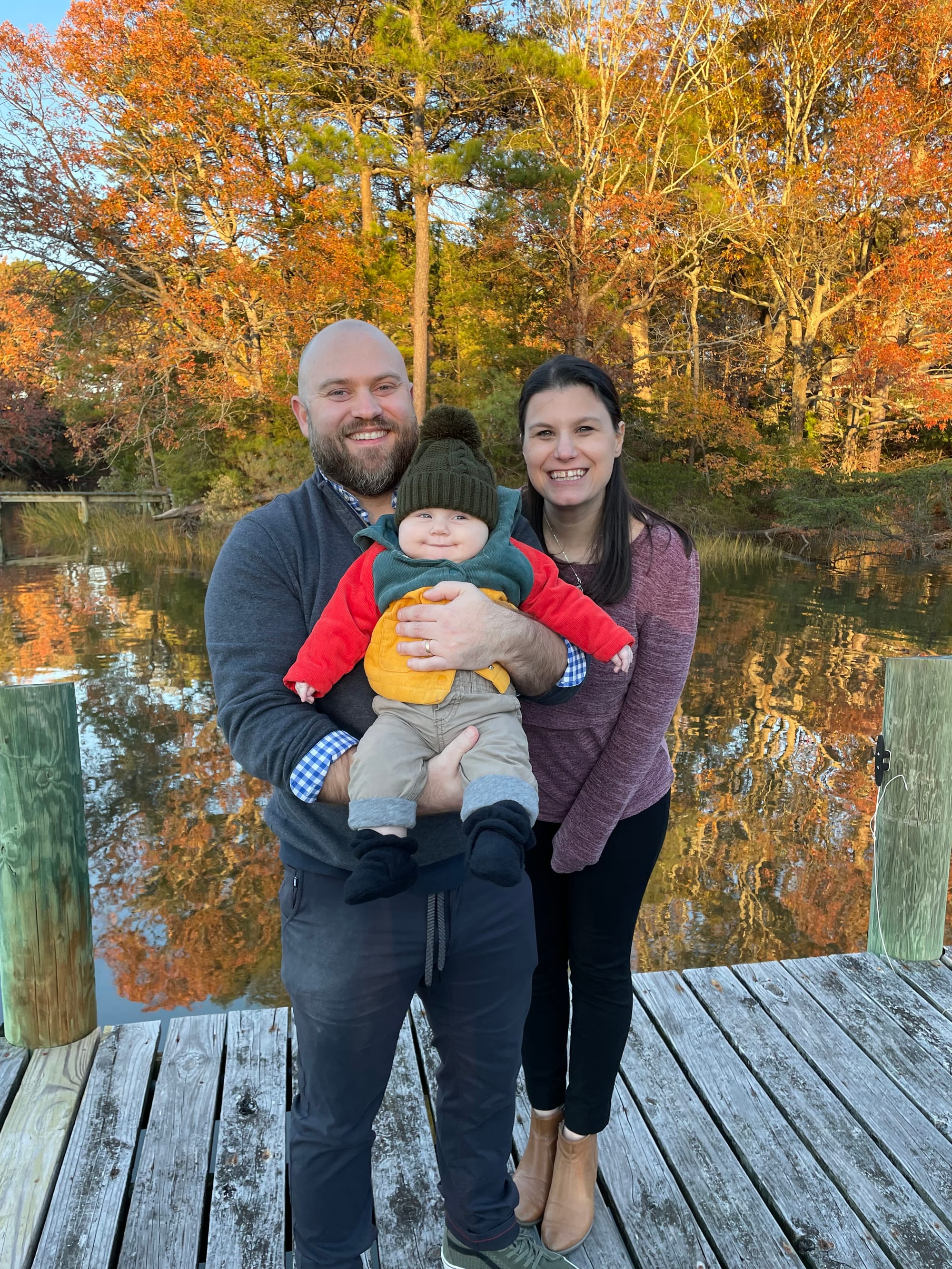 Frank and his family standing on a dock with fall foliage in the background.